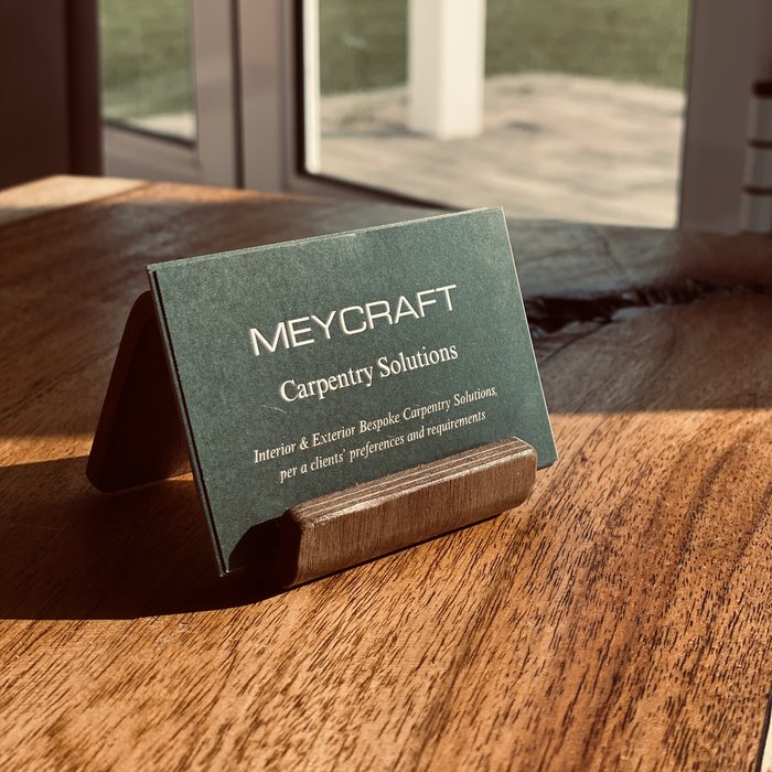 MeyCraft Carpentry Solutions business card standing on a handcrafted wood table